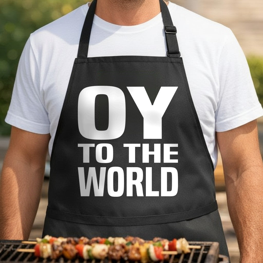 Black apron with large white text reading Oy To The World in bold capital letters, simple modern design.