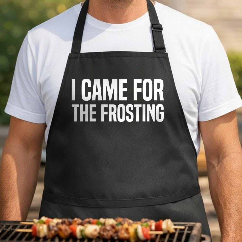 I Came for the Frosting black BBQ apron, torso close-up: Black apron with large white text saying 'I Came For The Frosting' in bold uppercase letters, simple and modern design.