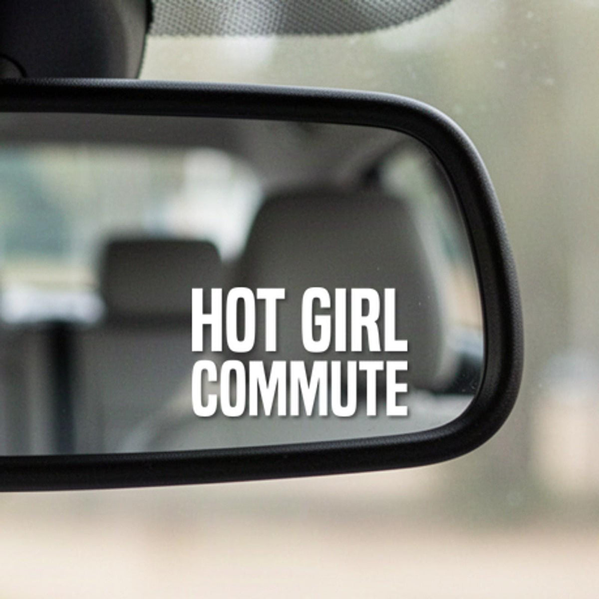 Close-up of the Hot Girl Commute white vinyl decal in the corner of a rear-view mirror