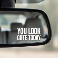Close-up of the You Look Cute Today white vinyl decal in the corner of a rear-view mirror
