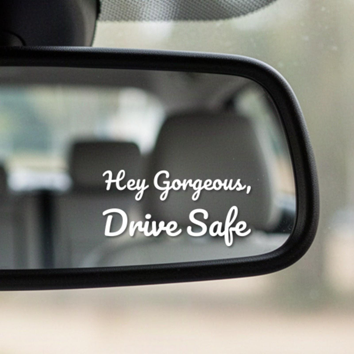 Close-up of the Hey Gorgeous, Drive Safe white vinyl decal in the corner of a rear-view mirror