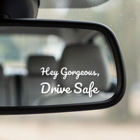 Close-up of the Hey Gorgeous, Drive Safe white vinyl decal in the corner of a rear-view mirror