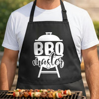 BBQ Master black BBQ apron, torso close-up: Black BBQ apron with white graphic of a kettle grill and bold text reading BBQ master in two fonts.