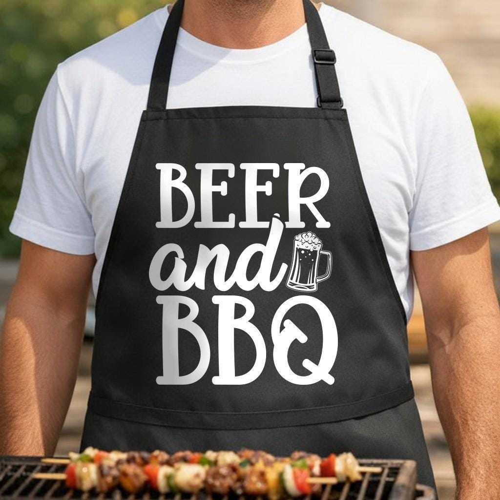 Beer and BBQ black BBQ apron, torso close-up: Black apron with white bold text reading 'Beer and BBQ' and a white graphic of a beer mug filled with foam.