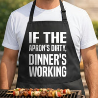 If the Apron's Dirty, Dinner's Working black BBQ apron, torso close-up: Owner-written slogan: "If the Apron's Dirty, Dinner's Working"